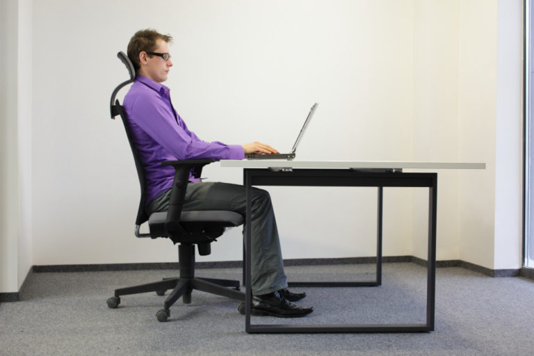 man doing work on his computer while sitting on a chair