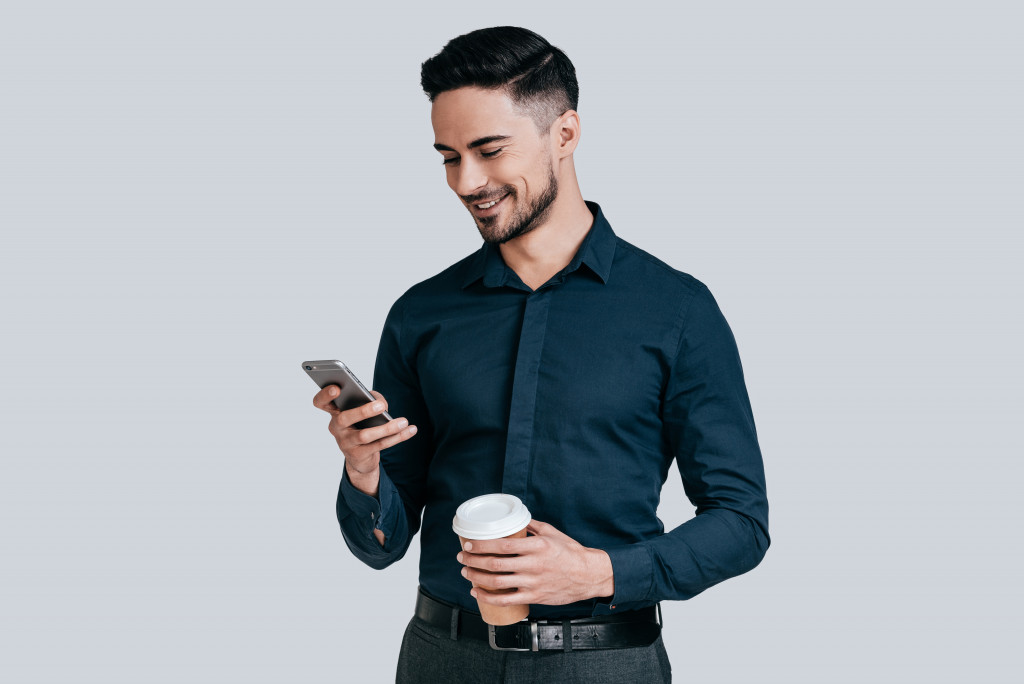 a person holding a phone and a cup of coffee