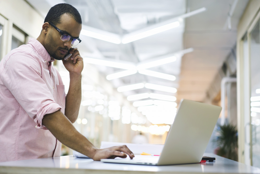 man using phone and laptop
