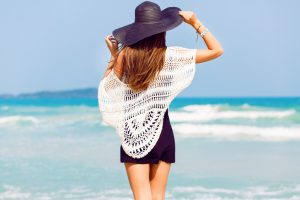 fashionista woman looking at beach with hat on