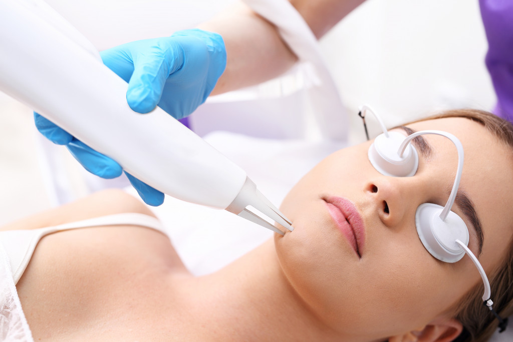 A woman getting a laser facial treatment in a spa