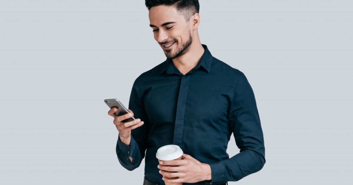 a person holding a phone and a cup of coffee