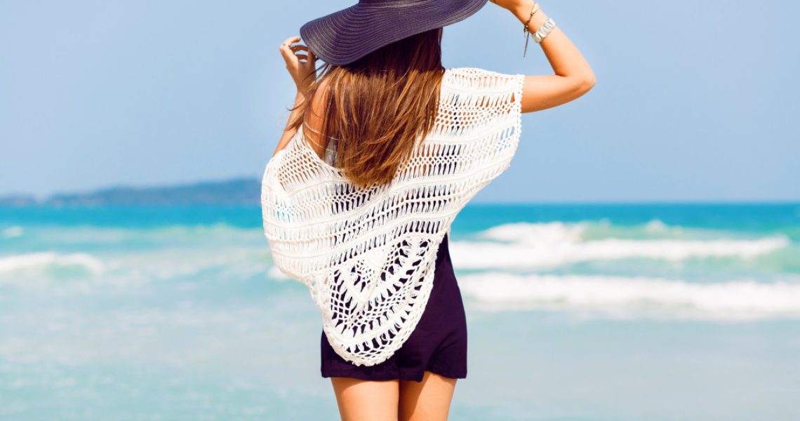 fashionista woman looking at beach with hat on